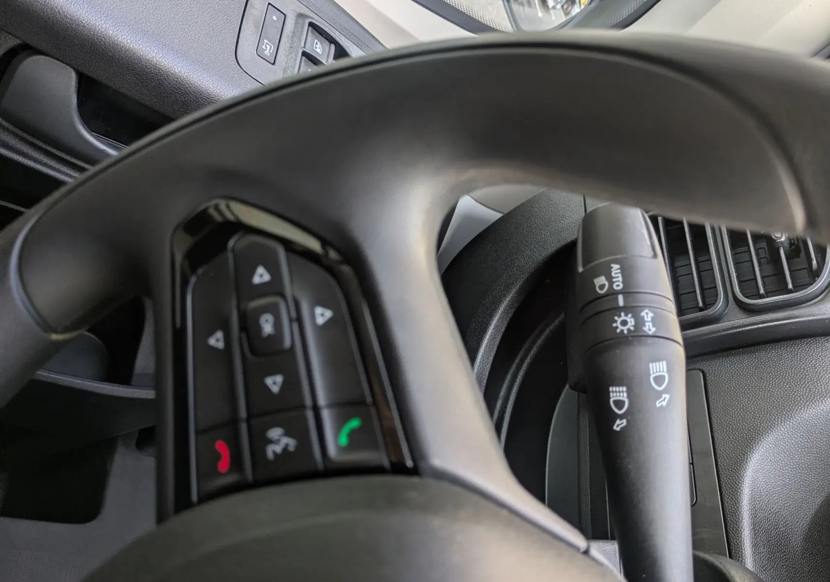 Vue intérieure rapprochée du volant et commande de phares du Peugeot Boxer Fourgon blanc, avec rétroviseur extérieur visible.