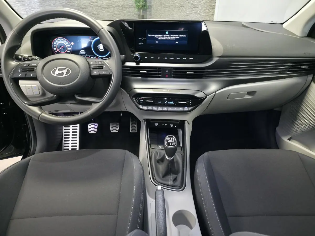 Vue intérieure avant du Hyundai Bayon 2025 noir, volant cuir, écran tactile 10,25'', boîte manuelle et console centrale épurée.