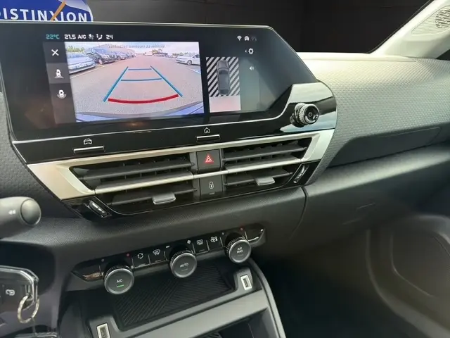 Vue intérieure du tableau de bord central de la Citroën C4 hybride 2025 avec écran tactile affichant l'aide au stationnement arrière.