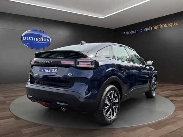 Citroën C4 hybride bleu en 3/4 arrière droit, avec feux LED et jantes alliage visibles en showroom.