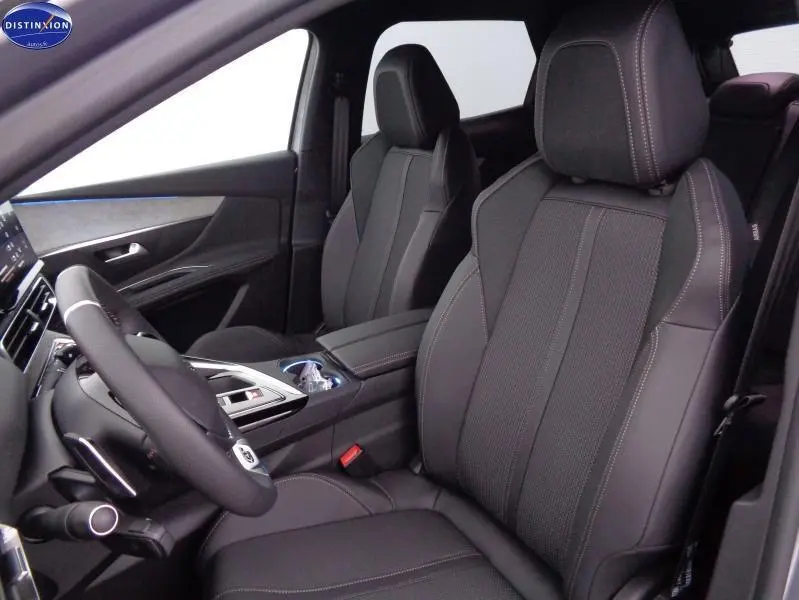 Vue intérieure côté conducteur du Peugeot 3008 2023, sièges en tissu noir avec surpiqûres contrastées et console centrale moderne.