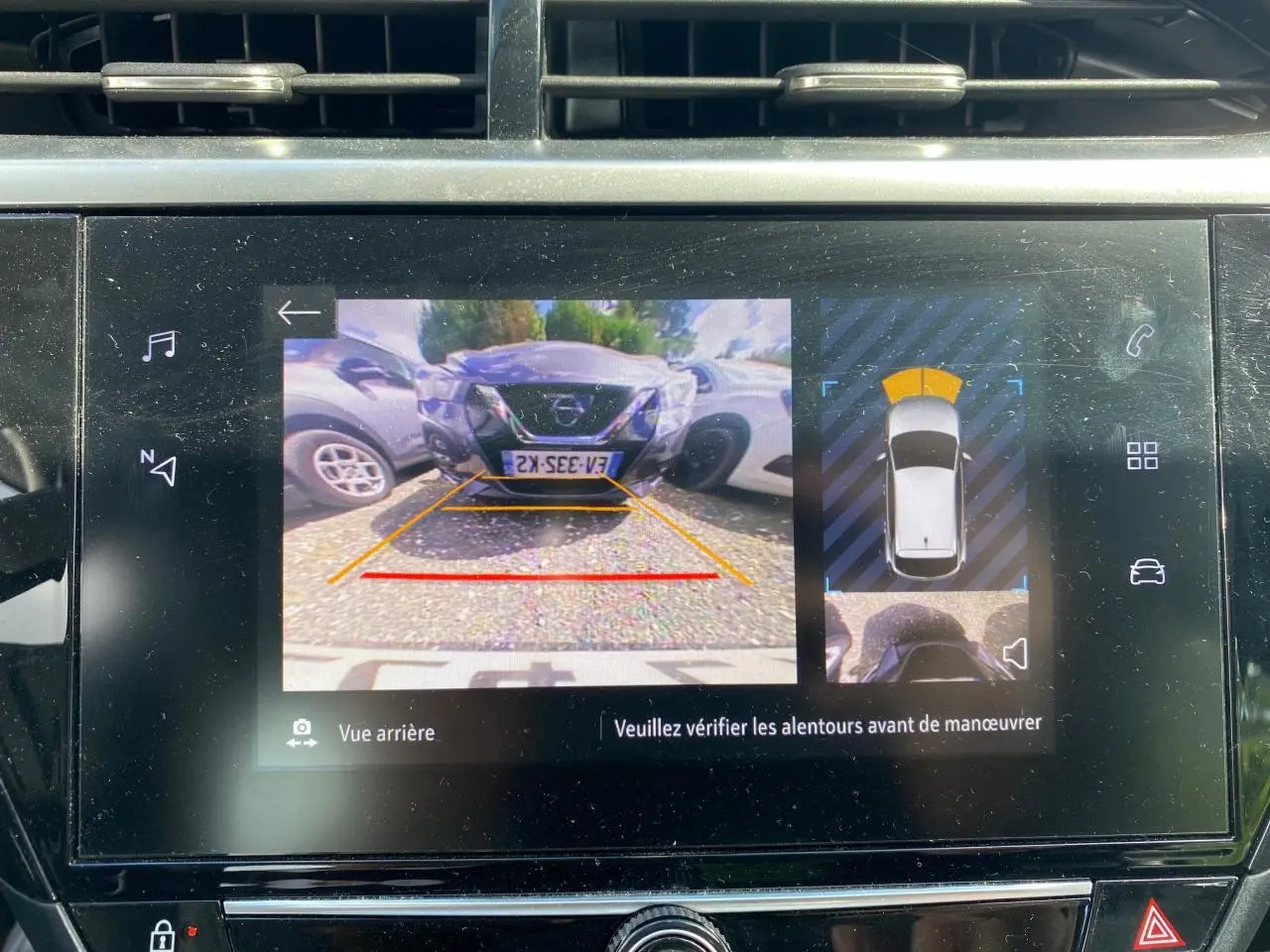 Écran digital de l'Opel Corsa bleu nautique montrant la caméra de recul avec vue arrière et aide au stationnement.