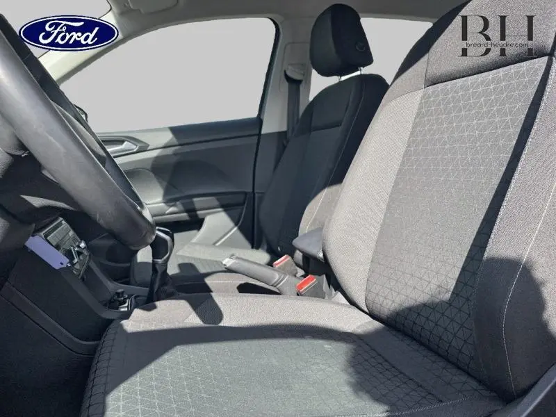 Intérieur avant du Volkswagen T-Cross 2022 montrant les sièges tissu gris et la console centrale avec levier de vitesse manuel.