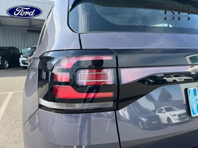 Gros plan sur le feu arrière gauche d'un Volkswagen T-cross gris cendré métallisé, soulignant son design moderne.