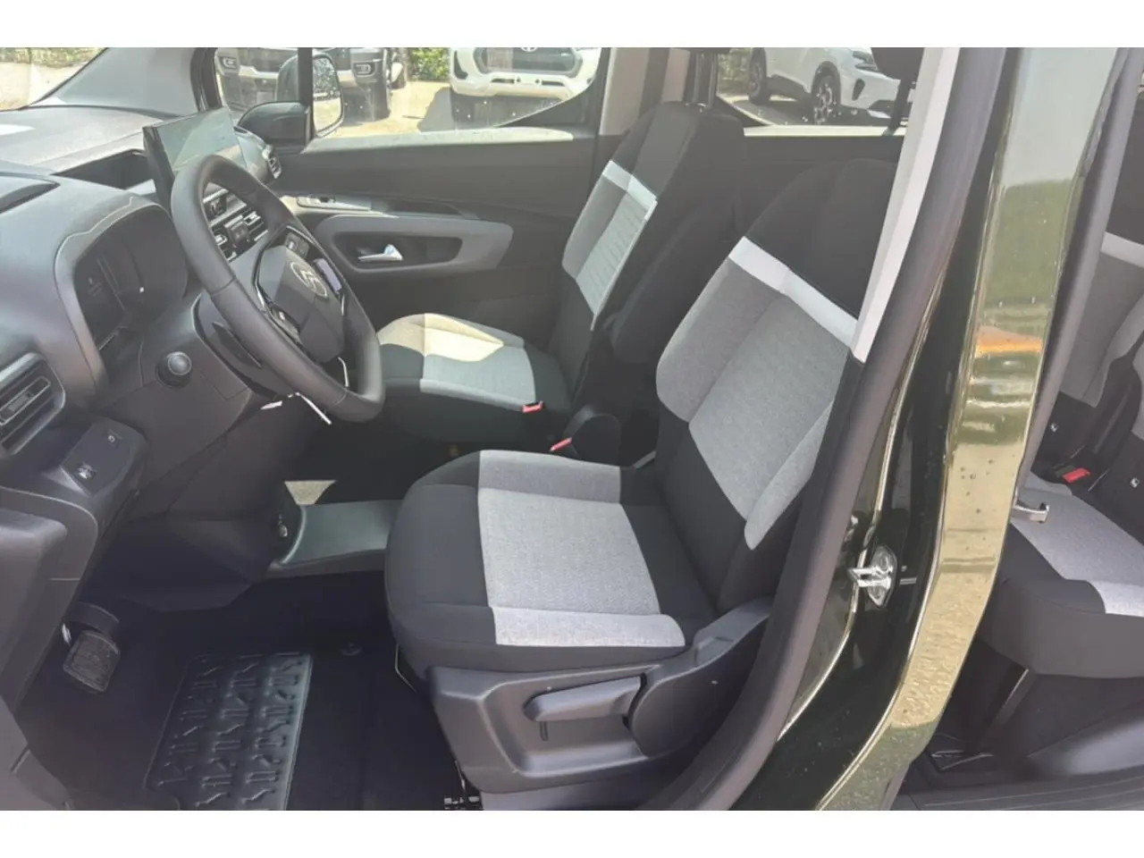 Vue intérieure côté conducteur du Citroën Berlingo 2025 vert Sirka, sièges tissu bicolore gris et noir.