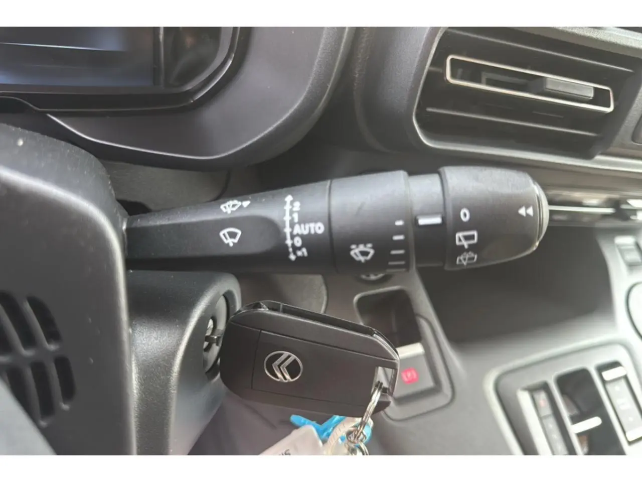 Gros plan sur la commande d'essuie-glace et la clé de contact du Citroën Berlingo 2025, intérieur noir.