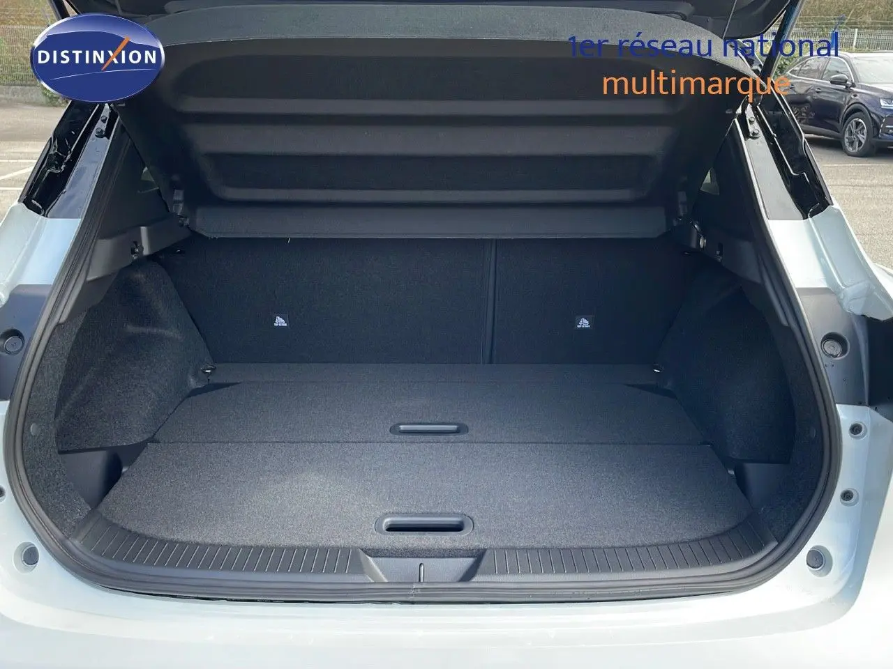 Coffre ouvert vu de l'arrière d'un Nissan Qashqai blanc nacré avec toit noir, montrant un espace de chargement plat et spacieux.