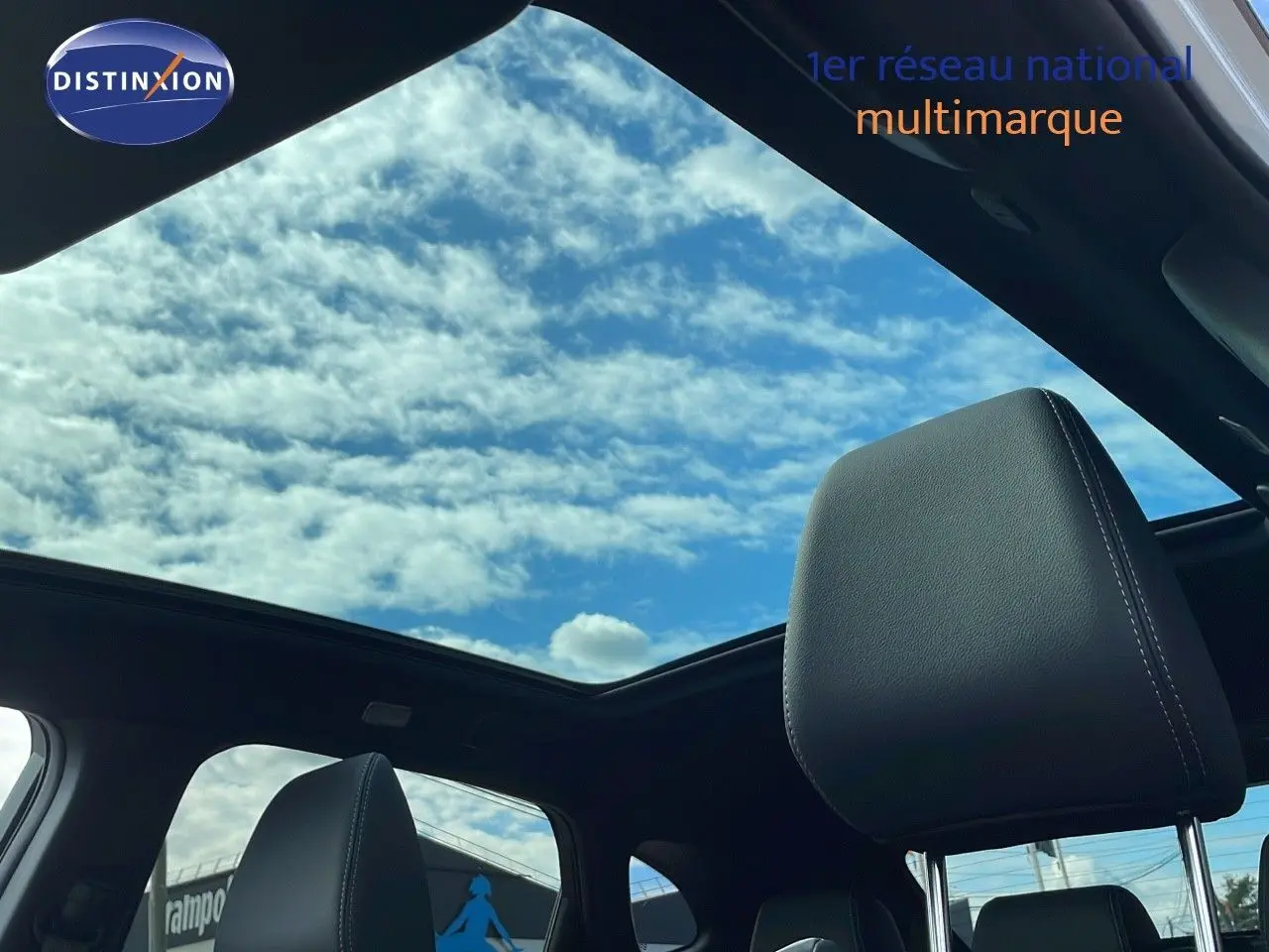 Vue intérieure du Nissan Qashqai 2025 blanc nacré avec toit noir, montrant le ciel à travers le toit panoramique et les appuis-tête cuir noir.