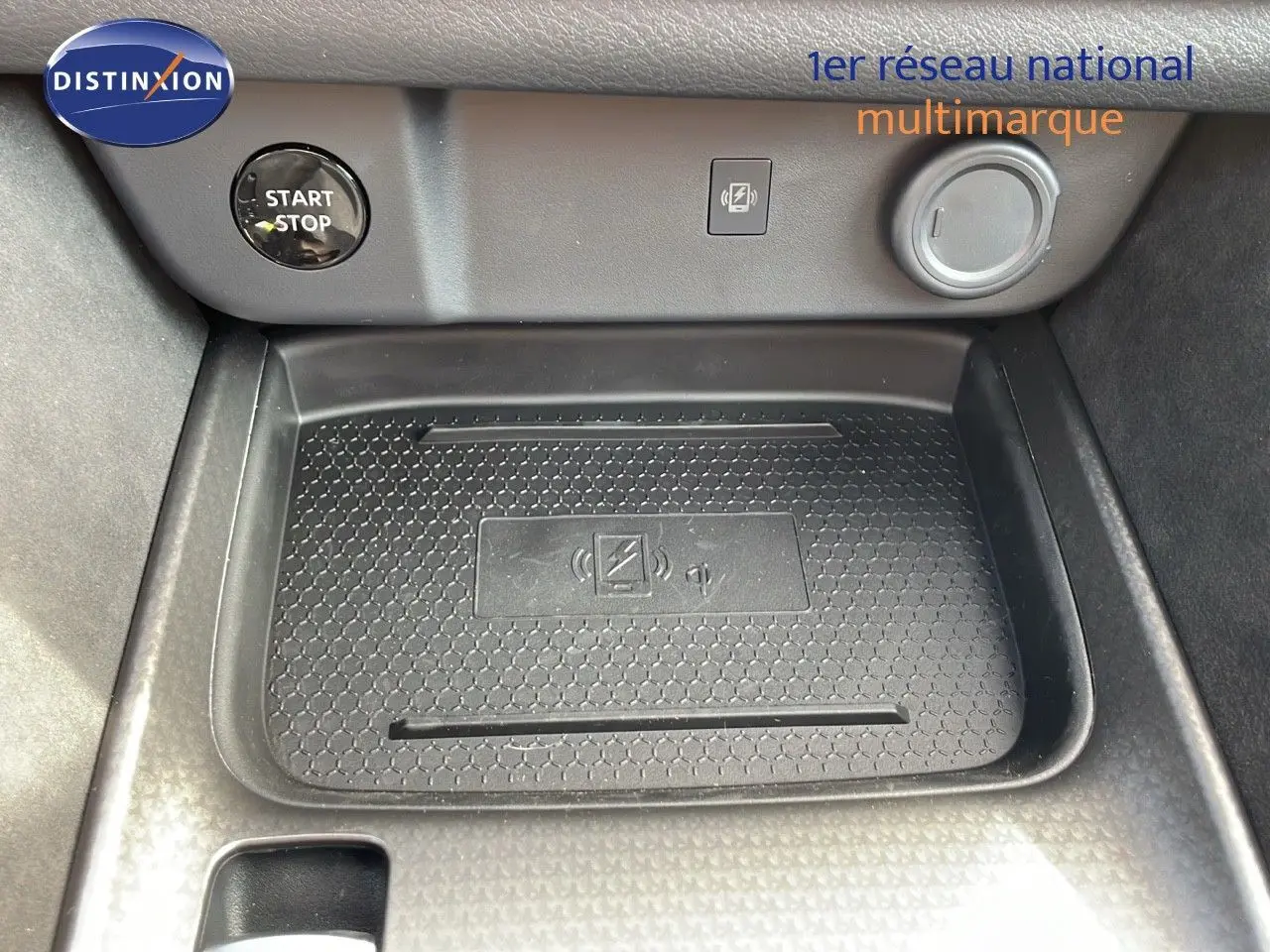 Gros plan sur la console centrale du Nissan Qashqai blanc nacré, montrant le bouton Start/Stop et le chargeur sans fil.