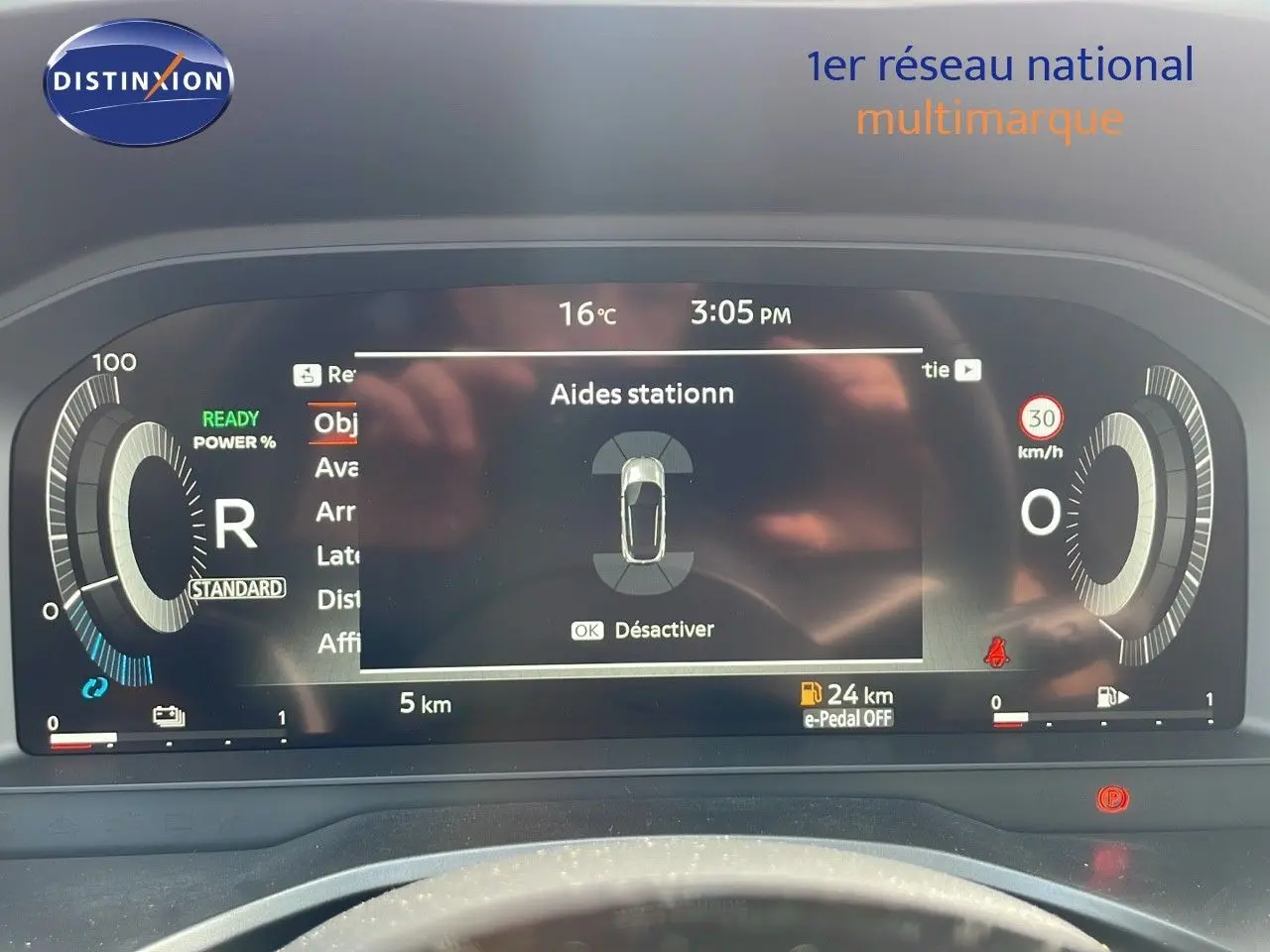 Tableau de bord numérique du Nissan Qashqai blanc nacré, affichant l'aide au stationnement et indicateurs de conduite.