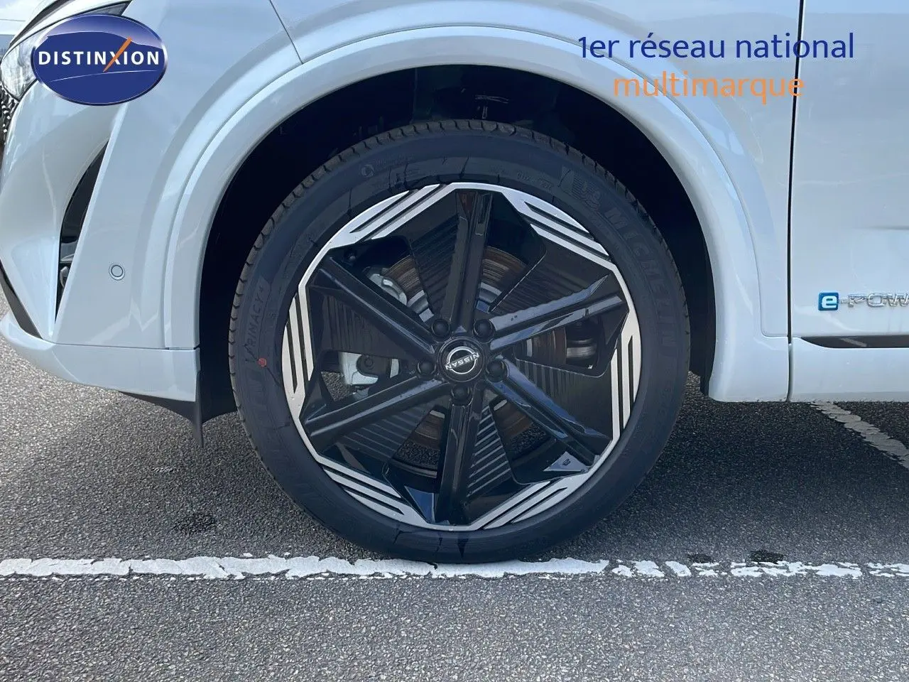 Gros plan sur la roue avant gauche du Nissan Qashqai blanc nacré avec jante noire et détails argentés.