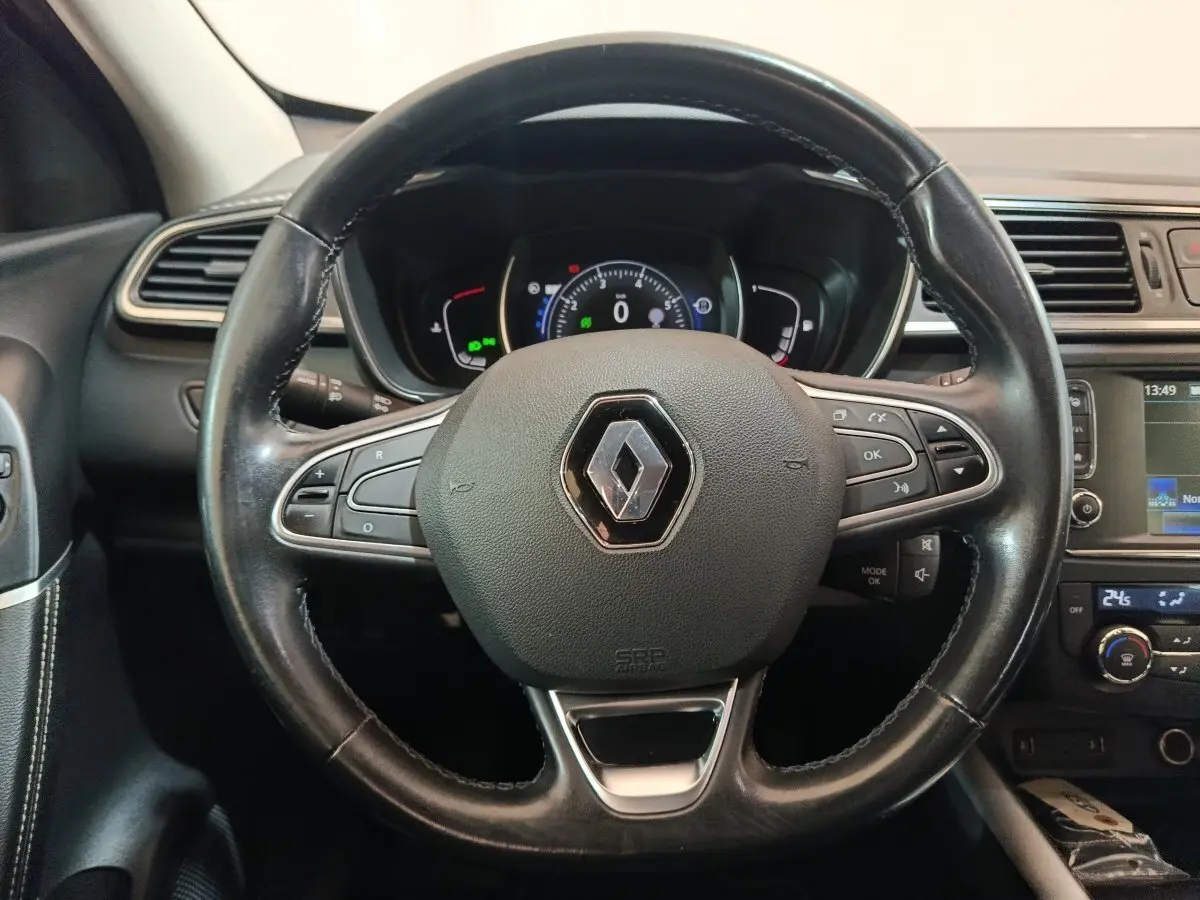 Volant cuir noir avec logo Renault au centre, tableau de bord numérique et écran tactile du Renault Kadjar Intens rouge 2017.