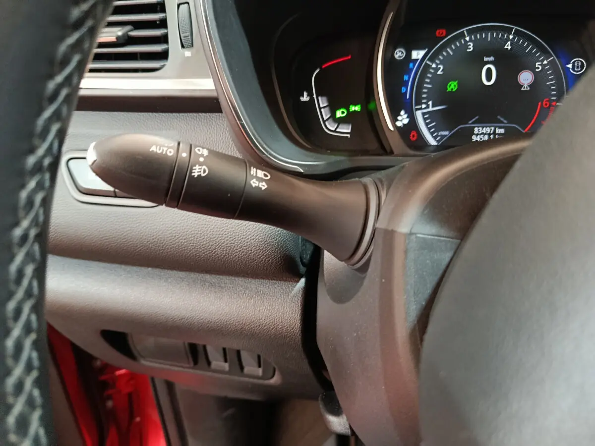 Gros plan sur le commodo d'éclairage à gauche du volant cuir du tableau de bord du Renault Kadjar rouge 2017.