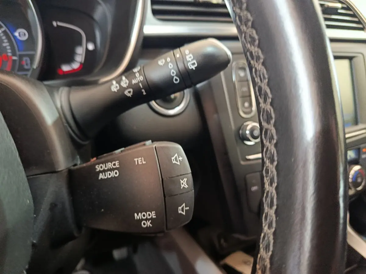 Gros plan sur les commandes audio et téléphone au volant cuir du Renault Kadjar Intens rouge, tableau de bord en arrière-plan.