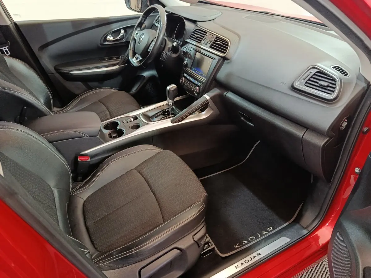 Intérieur côté passager du Renault Kadjar rouge, montrant sièges noirs et console centrale avec écran tactile.