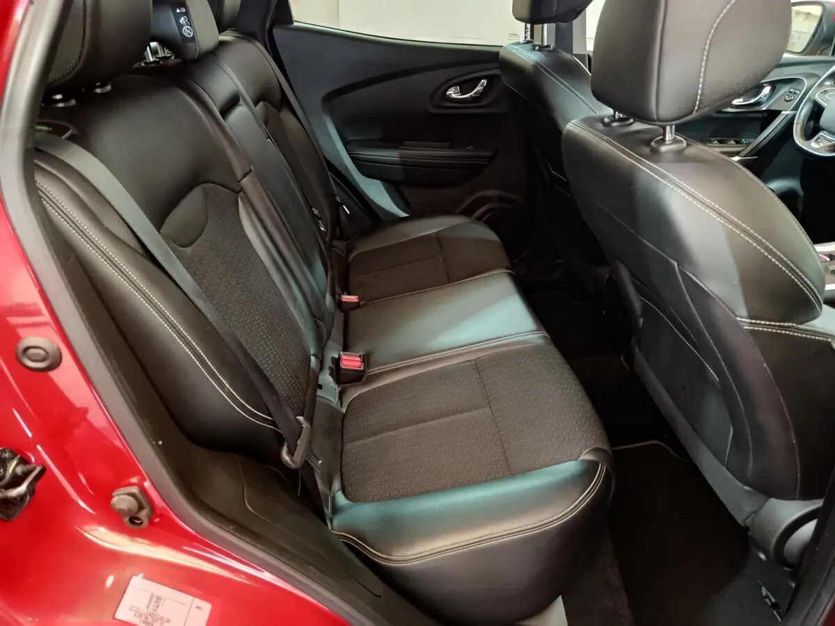 Vue intérieure côté arrière droit du Renault Kadjar Intens rouge, montrant les sièges en cuir noir avec surpiqûres blanches.