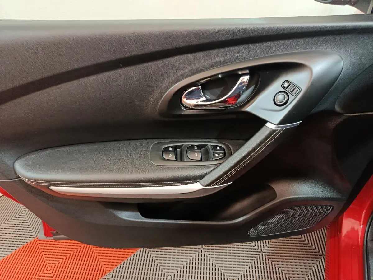 Poignée de porte intérieure côté gauche noire avec commandes électriques sur Renault Kadjar Intens rouge, vue rapprochée.