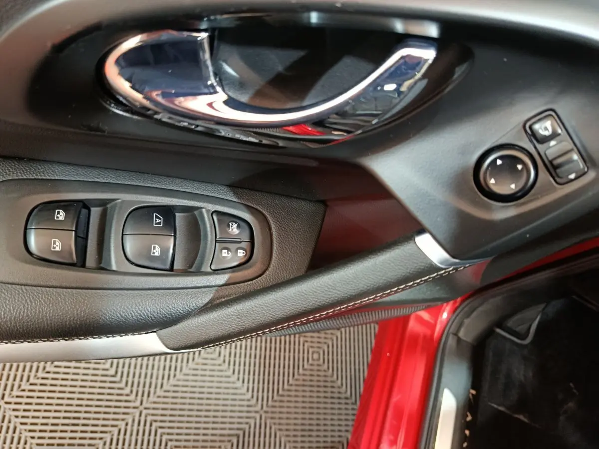 Gros plan sur la porte côté conducteur du Renault Kadjar rouge, montrant les commandes des vitres et rétroviseurs.