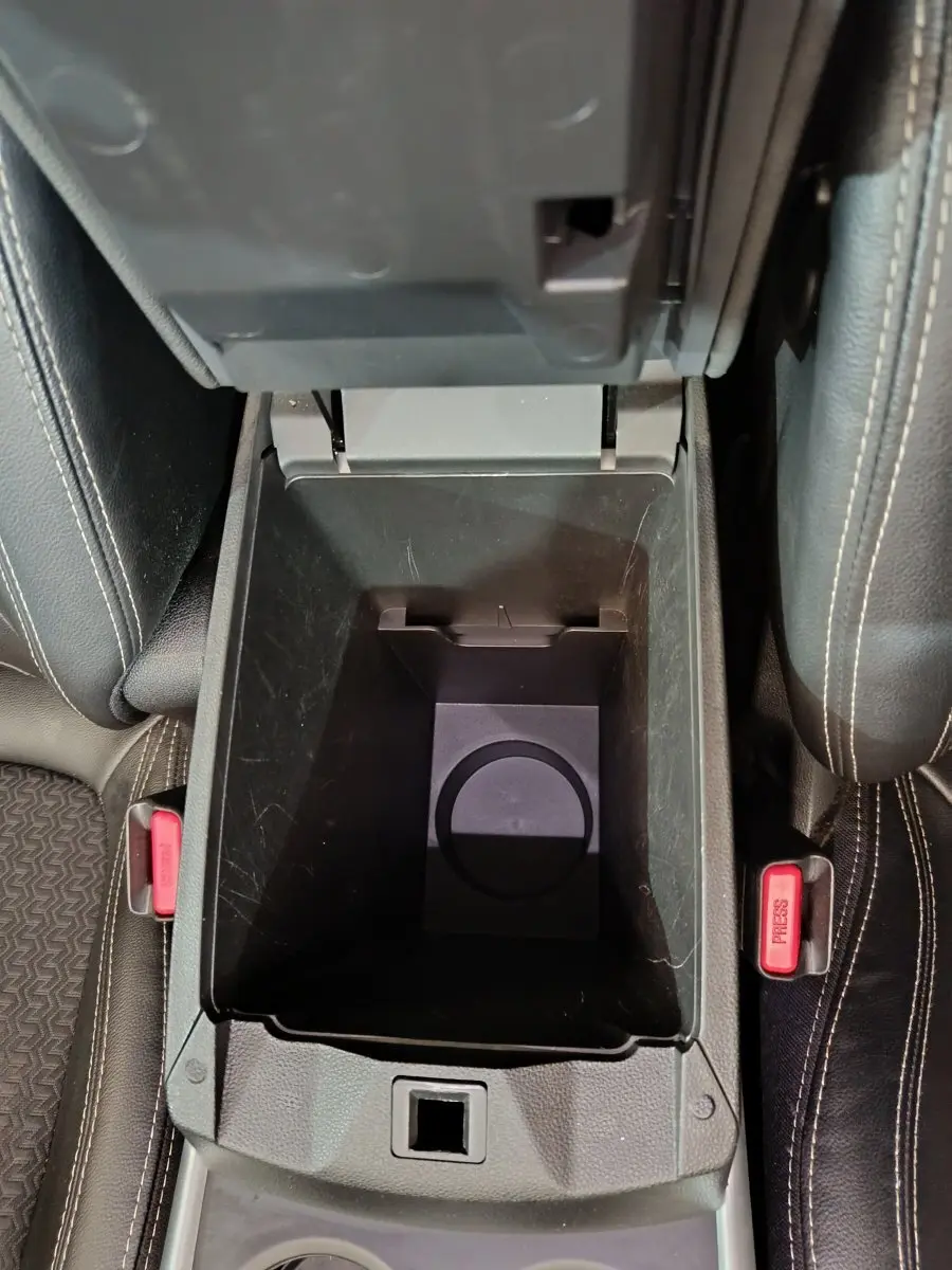 Vue plongeante sur la console centrale ouverte du Renault Kadjar Intens rouge, montrant le rangement intérieur et les ceintures de sécurité.