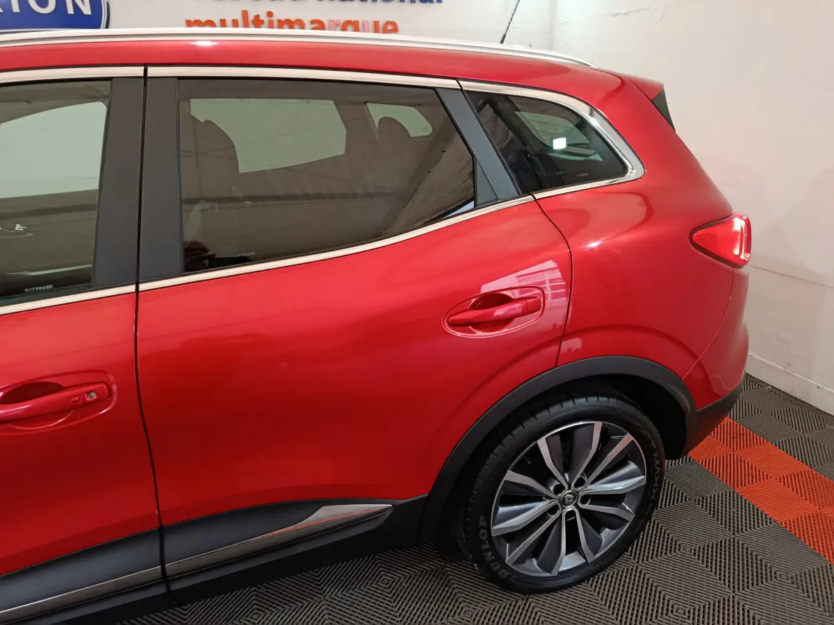 Vue latérale côté droit du Renault Kadjar rouge mettant en valeur la porte arrière et la roue arrière avec jante alliage.