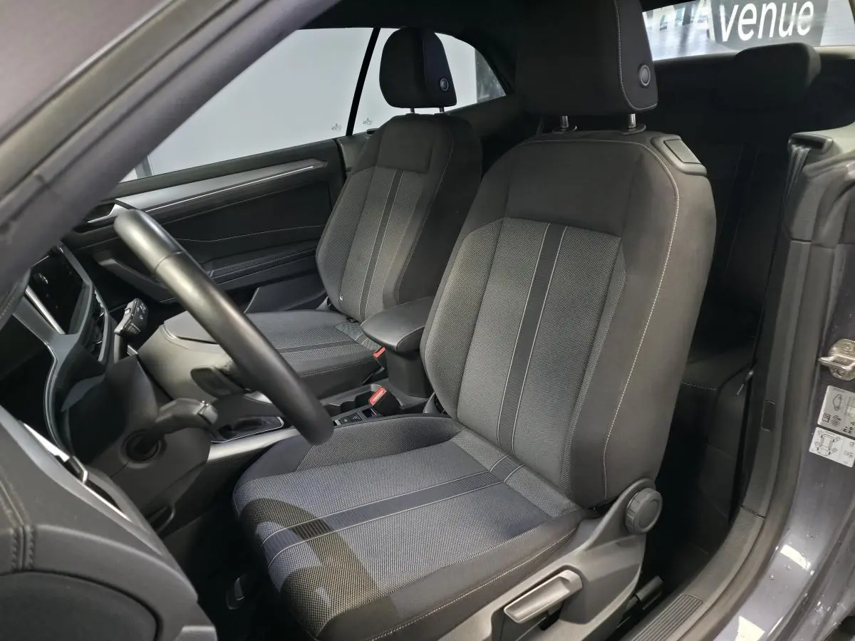 Intérieur du Volkswagen T-Roc Cabriolet gris 2024, vue côté conducteur sur les sièges avant en tissu noir et gris.