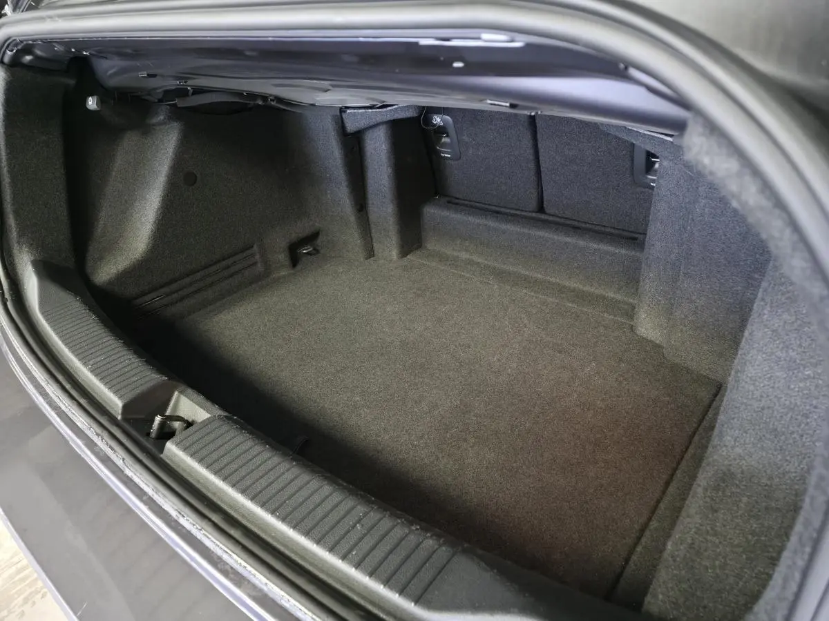 Coffre ouvert d'un Volkswagen T-Roc cabriolet gris 2024, montrant l'espace de rangement intérieur vide.