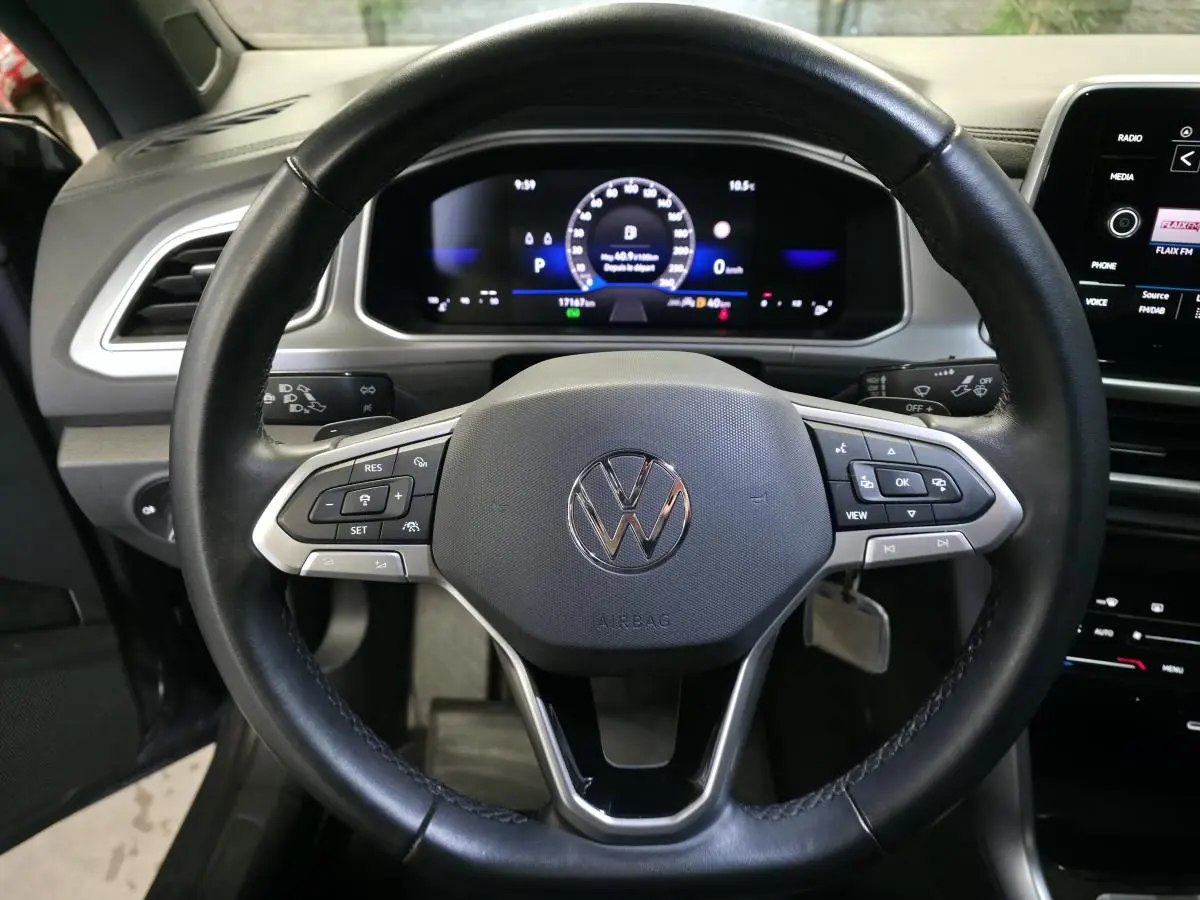 Volant en cuir multifonction noir avec logo Volkswagen, tableau de bord numérique et écran tactile du T-Roc Cabriolet gris 2024.