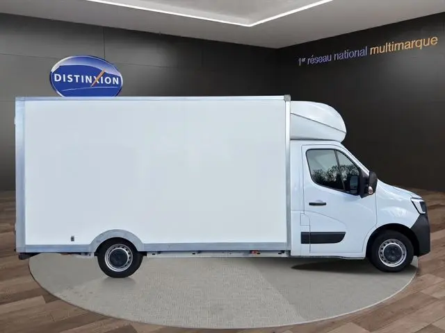 Vue latérale droite d’un Renault Master blanc 2023 avec caisse volumineuse en environnement showroom.