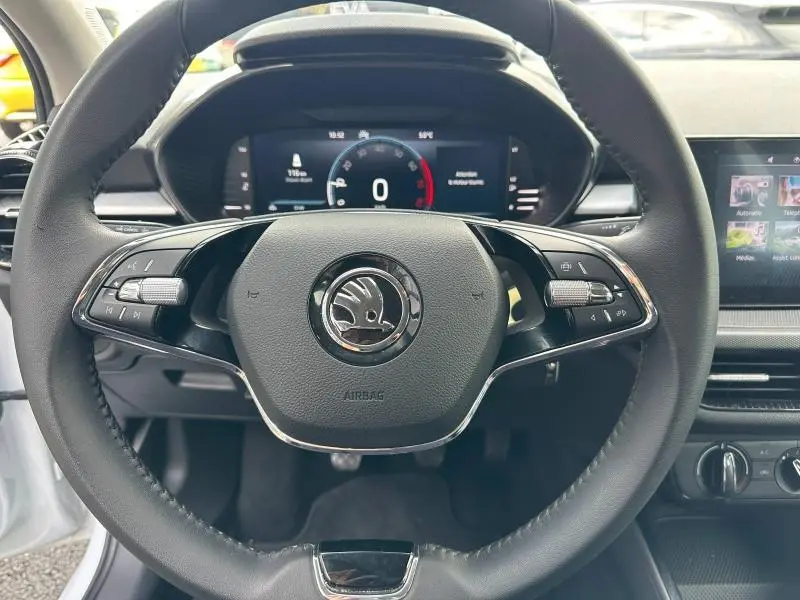 Vue rapprochée du volant cuir multifonction noir avec logo Skoda, tableau de bord digital et écran tactile d'une Fabia 2024.