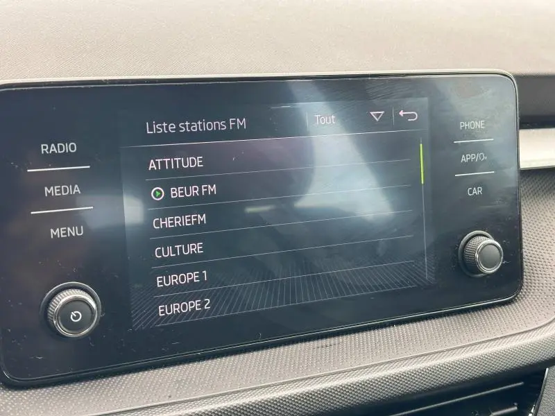 Écran tactile central affichant la liste des stations FM dans l'habitacle d'une Skoda Fabia bleu 2024.