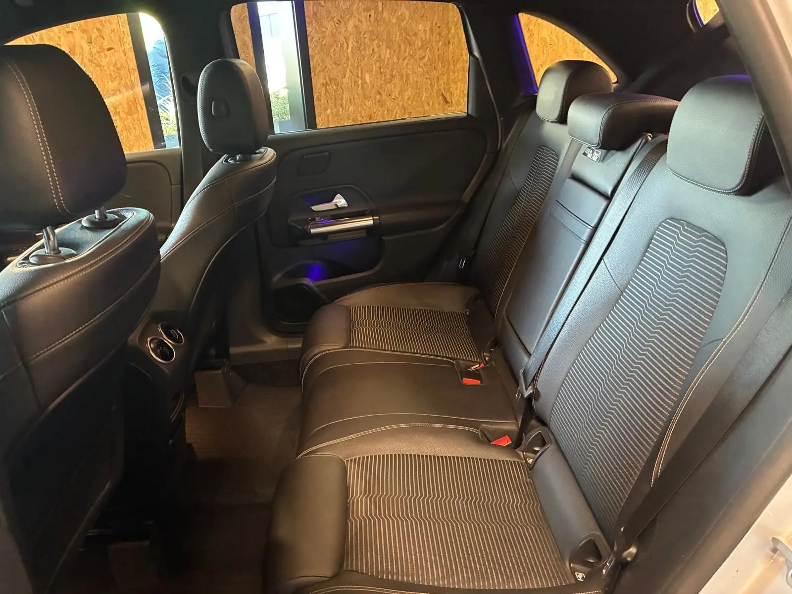Vue intérieure arrière côté droit de la Mercedes Classe B 200D Progressive Line avec sièges tissu gris noir et appuie-têtes.
