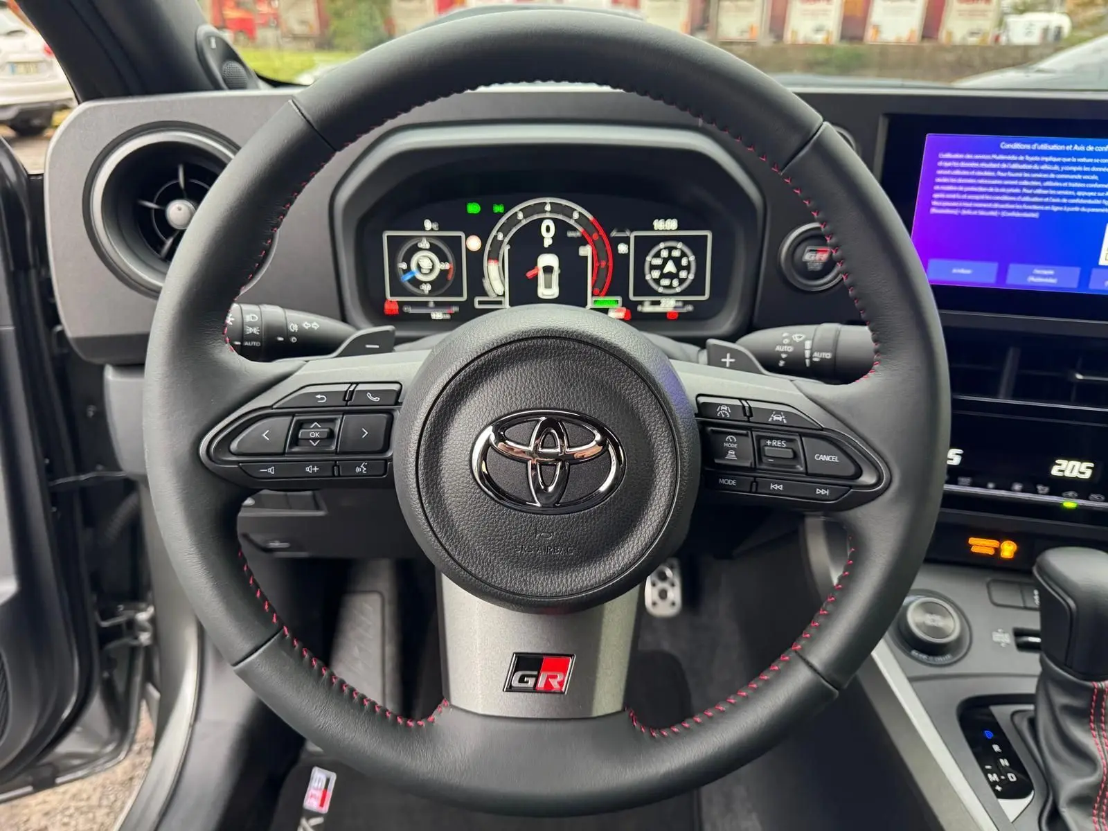 Vue rapprochée du volant noir avec surpiqûres rouges et logo GR de la Toyota Yaris GR Pack Techno.