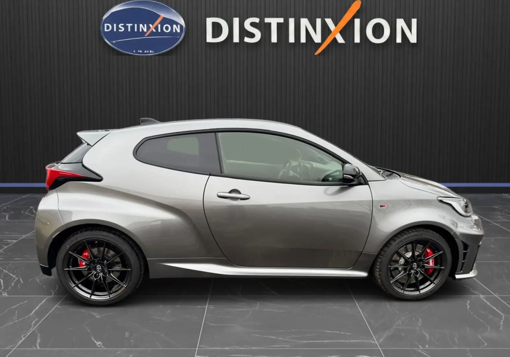 Profil droit de la Toyota Yaris GR gris platine avec jantes noires BBS et étriers de frein rouges visibles.