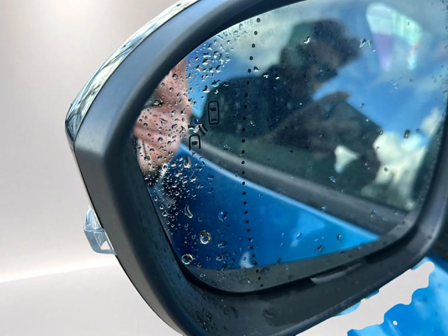 Rétroviseur extérieur côté gauche bleu outremer de Renault Austral 2026 avec gouttes d'eau et détection angle mort.