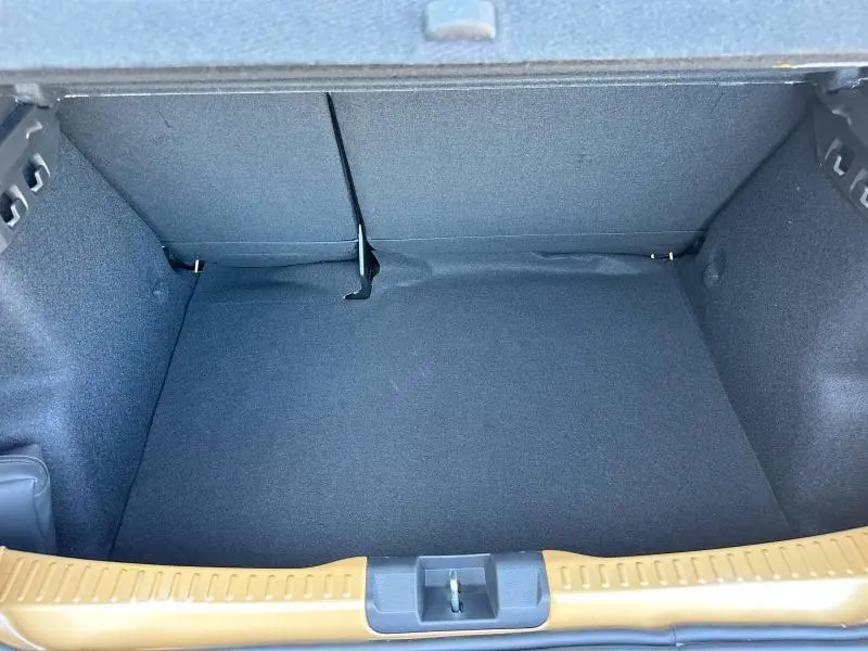 Coffre ouvert vu de dessus du Dacia Sandero beige Safari, montrant un espace de chargement vide et doublé de tissu noir.