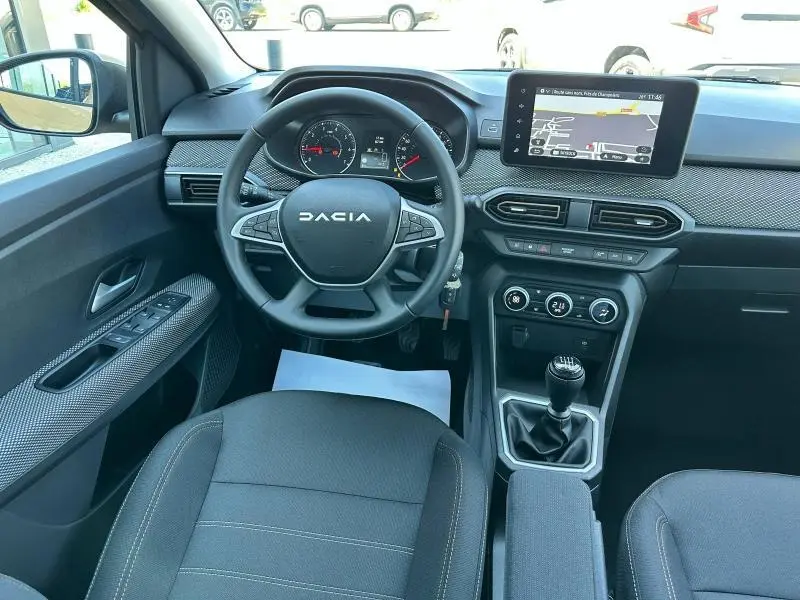 Intérieur avant de la Dacia Sandero 2025 avec tableau de bord moderne, volant multifonction et écran tactile central.