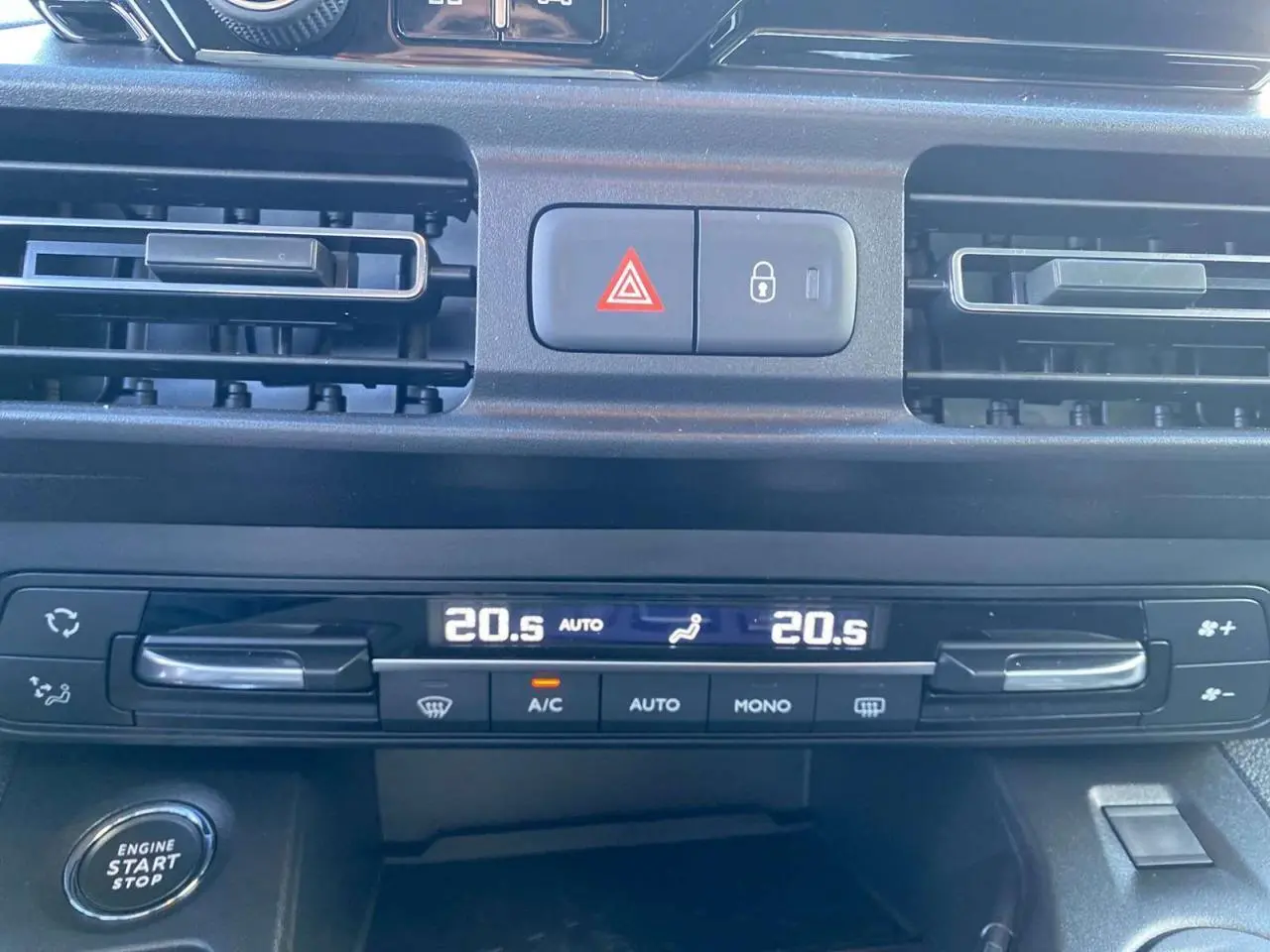 Détail du tableau de bord du Citroën Berlingo 2025 bleu, montrant la climatisation automatique bi-zone et le bouton start/stop.