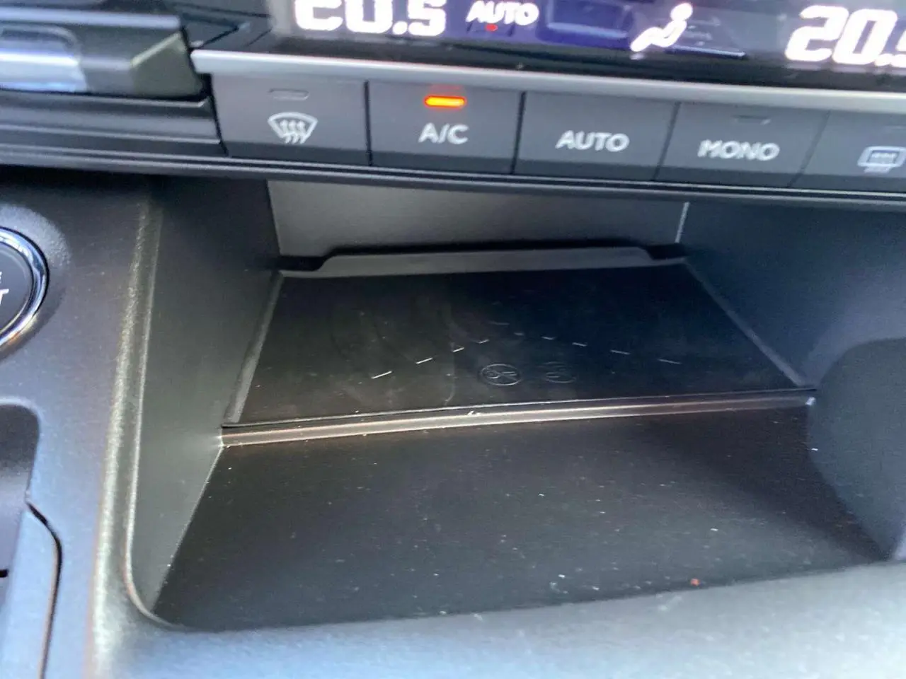 Gros plan sur la console centrale noire du Citroën Berlingo 2025, avec commandes climatisation et zone de rangement.