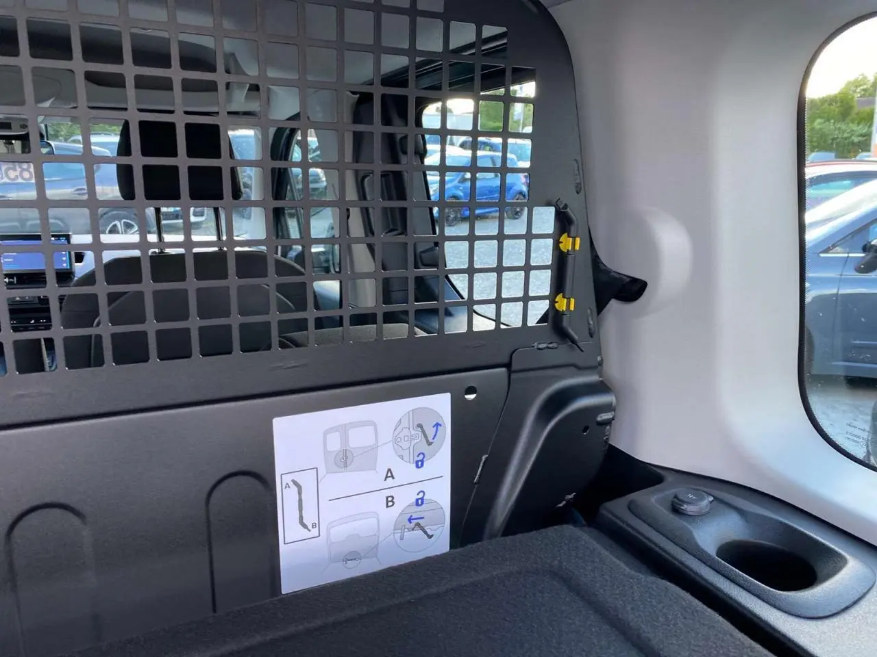Intérieur arrière du Citroën Berlingo bleu 2025, vue sur la grille de séparation et la fenêtre latérale droite.