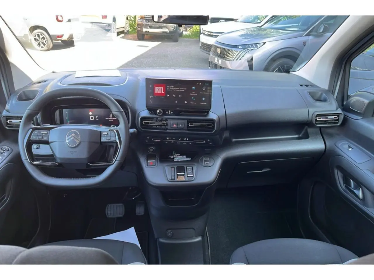 Intérieur du Citroën Berlingo 2025 vu de face, tableau de bord noir avec écran tactile central et volant multifonction.