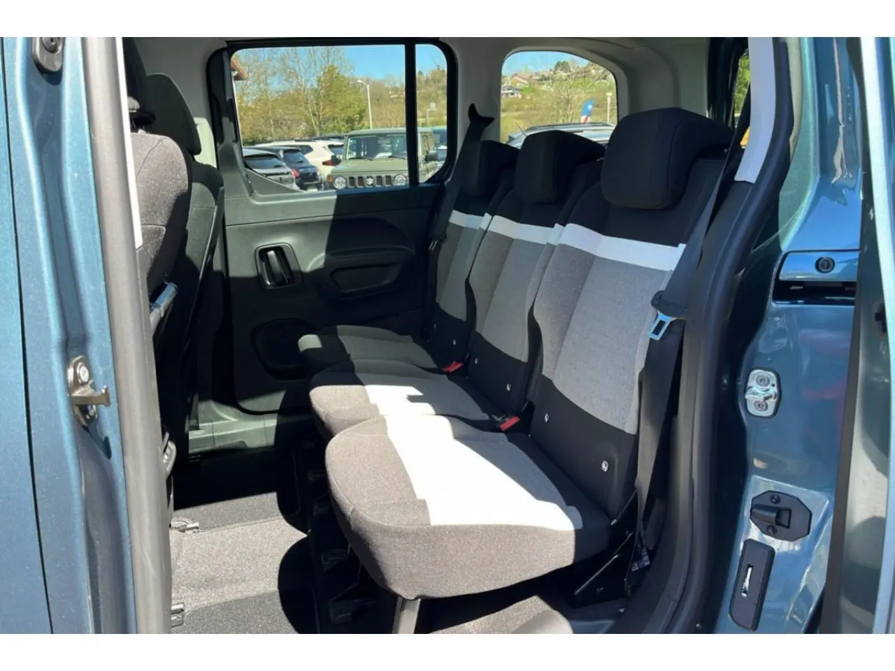 Vue latérale droite sur l'intérieur arrière bleu métallisé du Citroën Berlingo 2025 avec sièges tissu bicolores.