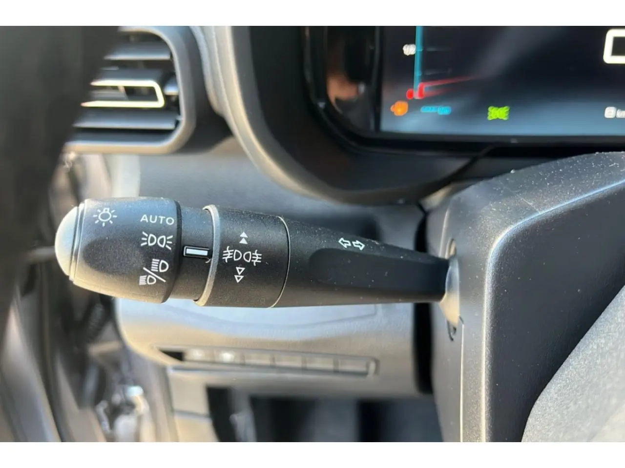 Gros plan sur la commande des feux et clignotants du tableau de bord du Citroën Berlingo bleu 2025.