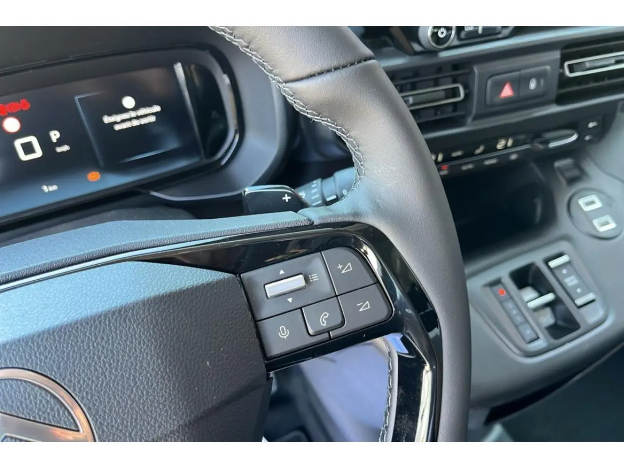 Gros plan sur le volant et le tableau de bord numérique du Citroën Berlingo bleu 2025 avec commandes au volant.
