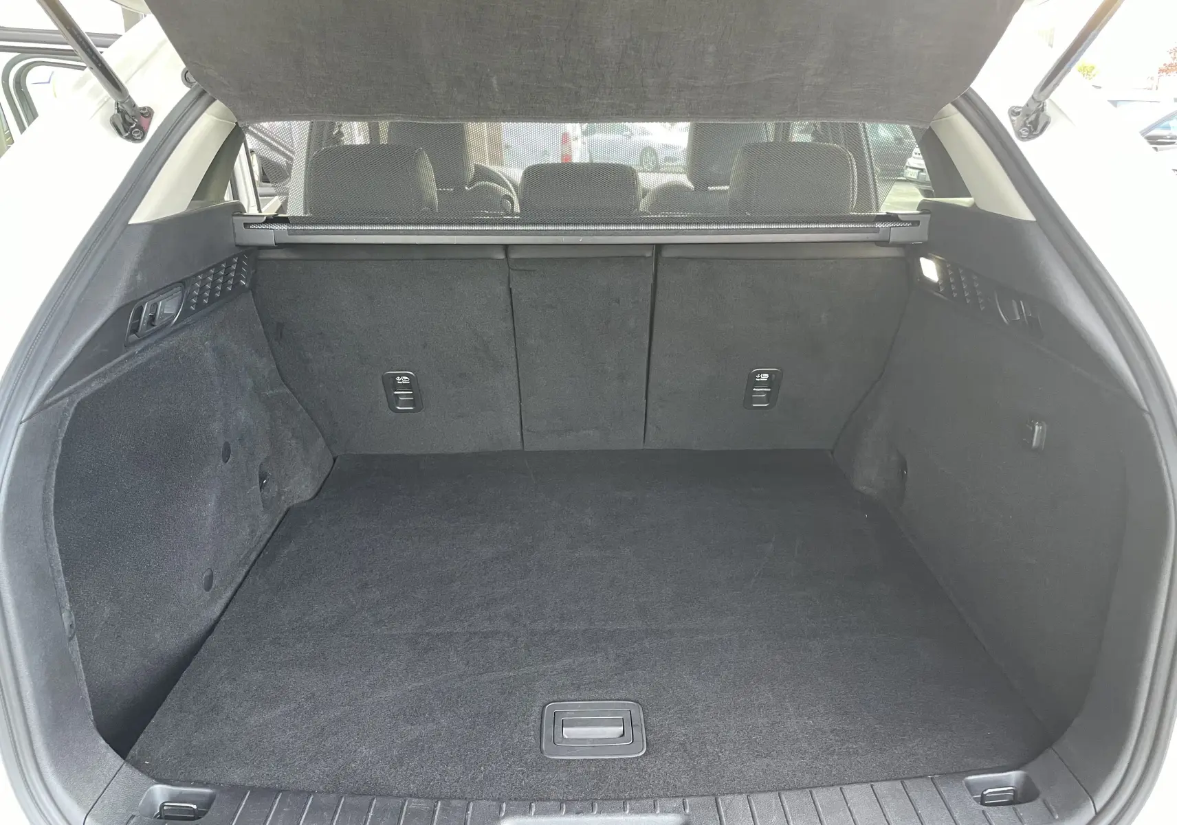 Vue intérieure du coffre spacieux et propre du Mazda CX-60 blanc nacré, avec banquette arrière et cache-bagages visibles.
