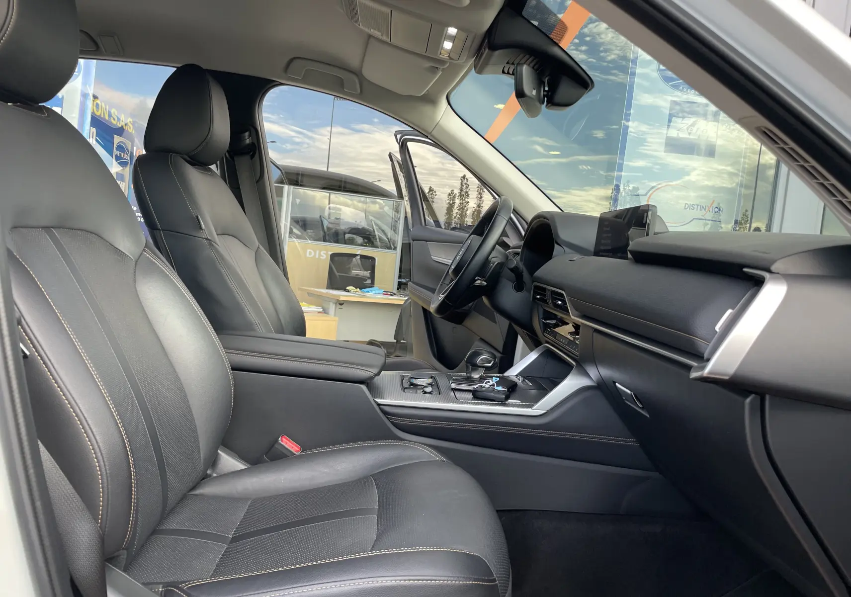 Vue intérieure côté conducteur du Mazda CX-60 blanc nacré 2023, avec sièges cuir noirs et tableau de bord moderne.