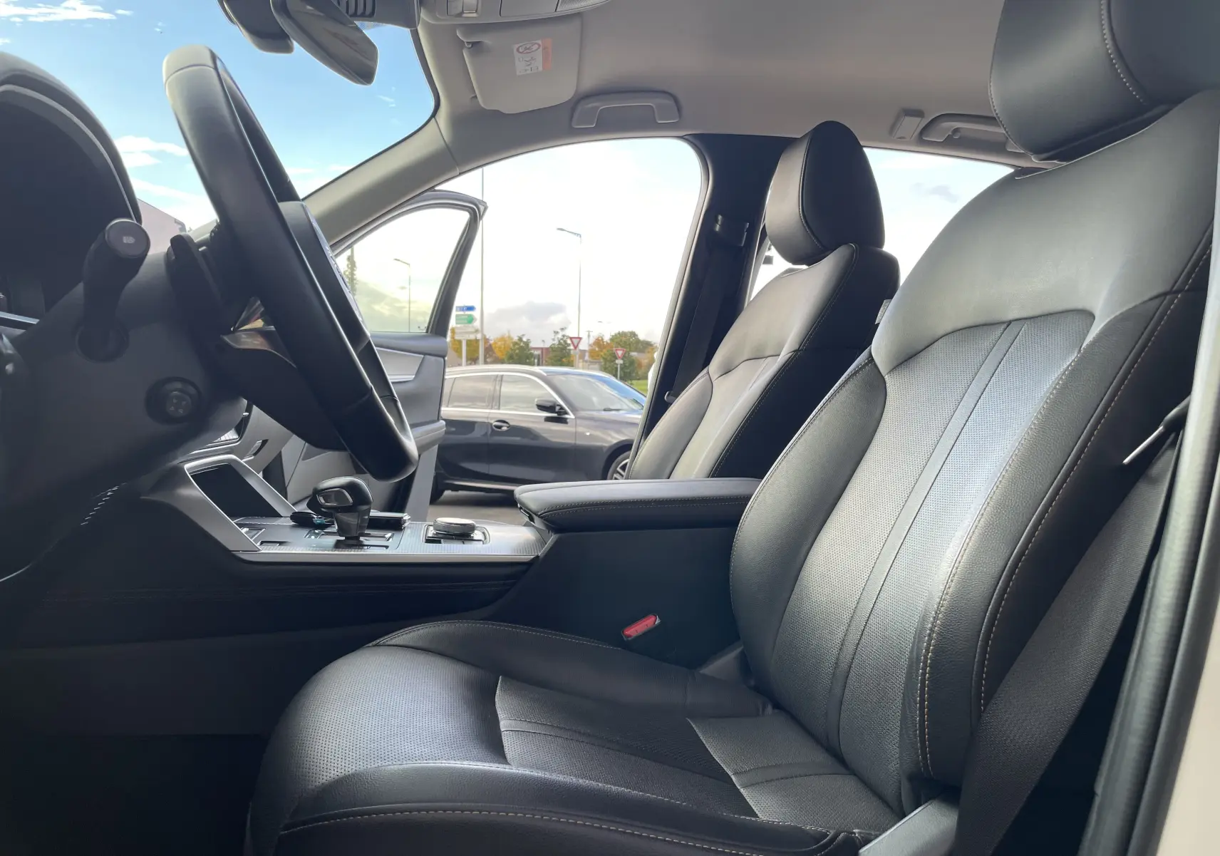 Vue intérieure côté conducteur du Mazda CX-60 blanc nacré 2023, sièges cuir noirs et console centrale avec levier de vitesses.