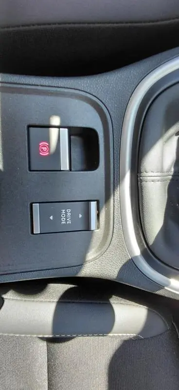 Gros plan sur la console centrale du Jeep Avenger blanc 2025, montrant les boutons frein électronique et mode de conduite.