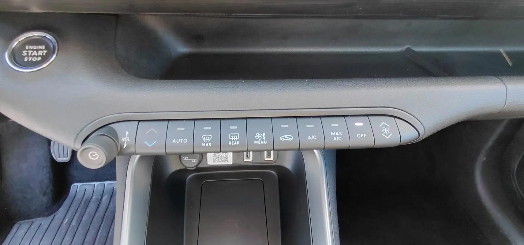 Vue rapprochée de la console centrale du Jeep Avenger blanc 2025, montrant les commandes de climatisation et le bouton start/stop.