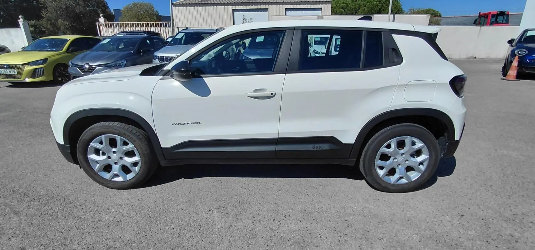 Jeep Avenger blanc en vue de profil côté gauche, avec protections noires sur les bas de caisse et les passages de roues.