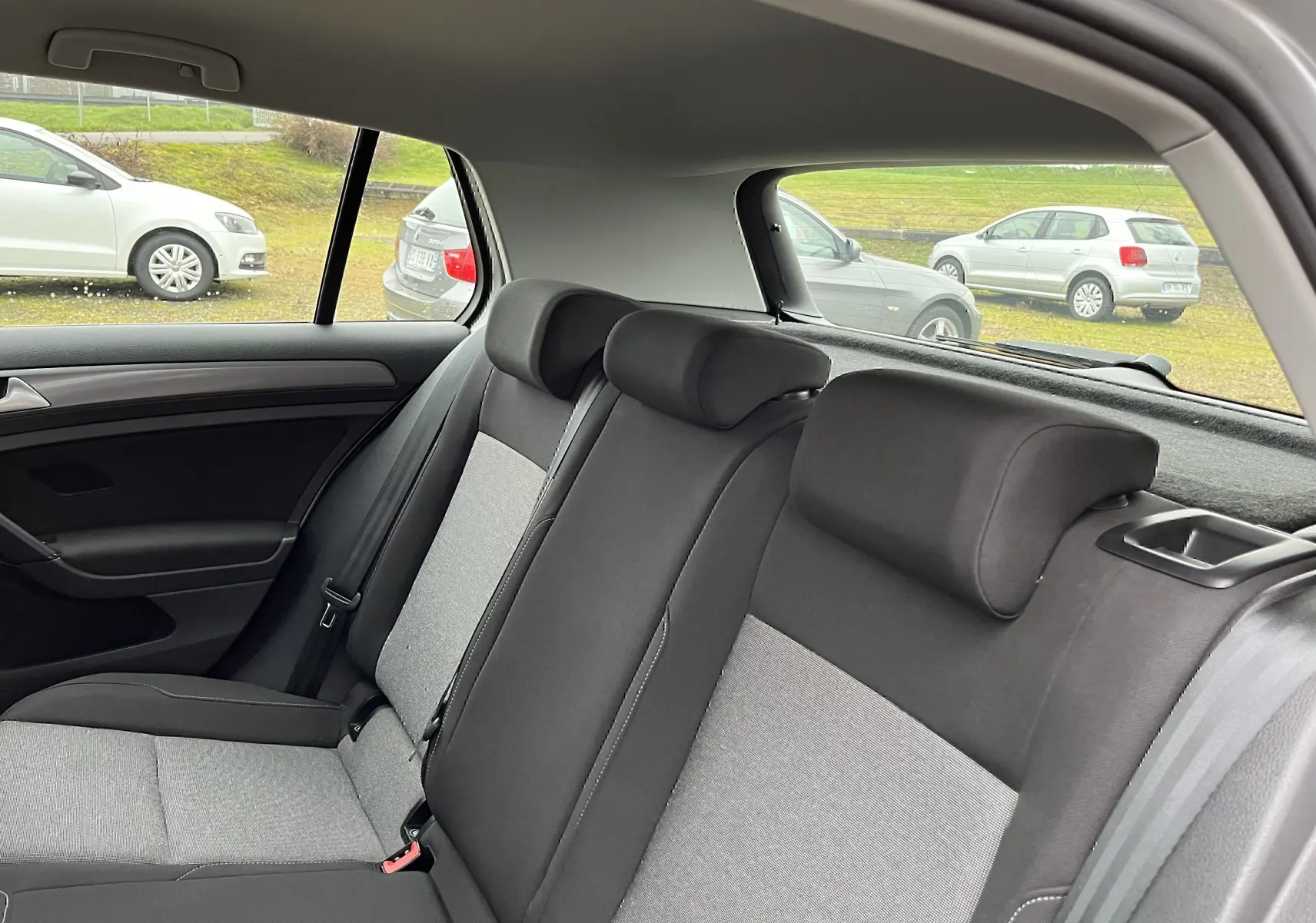 Vue intérieure arrière montrant les sièges en tissu noir et gris de la Volkswagen Golf 7 Trendline 2017.